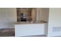 Kitchen boasts a breakfast bar, stainless steel appliances, and gray cabinets at 1807 Don Pl, Poinciana, FL 34759