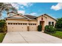 Tan house with three-car garage and neatly landscaped front yard at 30120 Hackney Loop, Mount Dora, FL 32757