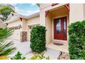 Red front door with glass accents and nicely manicured bushes at 30120 Hackney Loop, Mount Dora, FL 32757