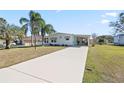 Exterior view of home with a long driveway, front lawn, and tropical landscaping at 906 Beechwood Ave, Lady Lake, FL 32159