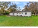 Back of a single-story home featuring a lush lawn, mature trees and a white painted brick exterior at 3800 Levins Rd, Mulberry, FL 33860