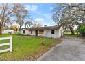 Single-story home featuring a white painted brick exterior, mature trees and large front yard at 3800 Levins Rd, Mulberry, FL 33860