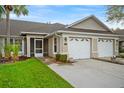 Charming home exterior features a well-manicured lawn and attached two-car garage at 26922 White Plains Way, Leesburg, FL 34748