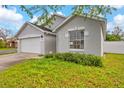 Well-kept gray home with a two-car garage and beautiful green lawn and tidy shrubbery at 580 Tree Shore Dr, Orlando, FL 32825