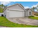 Gray home showcasing a two-car garage, green lawn, and front yard, with ample parking space at 580 Tree Shore Dr, Orlando, FL 32825