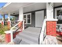 Close-up of front porch featuring brick columns, gray steps, and a classic white front door at 1309 Sanford Ave, Sanford, FL 32771