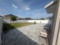 Spacious backyard with a white fence, a well-maintained lawn, and a large stone-paved patio area with chairs at 308 Aberdeen Dr, Davenport, FL 33896