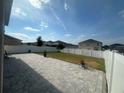 The fenced backyard has a large paved patio, a grass lawn, and lush landscaping under a sunny sky at 308 Aberdeen Dr, Davenport, FL 33896