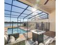 Relaxing screened pool area boasts brick pool deck, blue tiled pool, and outdoor fire table at 8882 Geneve Ct, Kissimmee, FL 34747