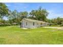 Single-story home with spacious green lawn, patio and mature trees at 1143 Ne 23Rd St, Ocala, FL 34470