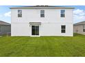 A view of the back of a two-story house with a sliding glass door and a green lawn at 2222 Oklahoma Dr, Sumterville, FL 33585