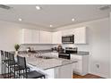 Modern kitchen with white cabinets, stainless steel appliances, granite countertops, and a breakfast bar at 2383 Oklahoma Dr, Sumterville, FL 33585
