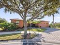 One-story house with orange exterior, mature landscaping, and paver driveway at 112 Sevilla Ct, Poinciana, FL 34759