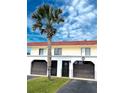 Charming two-story home with red roof, attached garages, a palm tree, and a manicured lawn at 64 Ocean Palm S Dr # 64, Flagler Beach, FL 32136