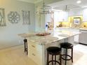Bright kitchen island with granite countertop, bar stool seating, decorative lighting, and ample cabinet storage at 64 Ocean Palm S Dr # 64, Flagler Beach, FL 32136