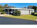 Mobile home with carport, screen enclosure, and well-maintained lawn at 215 Rue De Paresse, Tavares, FL 32778