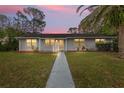 Gray ranch home with walkway, landscaping, and palm trees at dusk at 89 Hickory Hills Cir, Ormond Beach, FL 32174