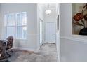 Bright hallway with decorative wall trim, neutral paint, and beautiful tile flooring leads to white doors at 1510 Kinnard Cir, Ormond Beach, FL 32174
