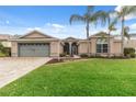 Front view of a single story house with a gray garage door and palm trees at 4546 Nottoway Dr, Leesburg, FL 34748