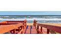 Red wooden walkway leading to a sandy beach at 3370 Ocean Shore Blvd # 3060, Ormond Beach, FL 32176