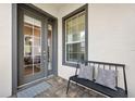 Inviting front porch with a bench, cushions, a new door, and brick flooring at 820 Aldenham Ln, Ormond Beach, FL 32174