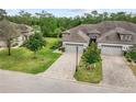 Two-story house with gray roof and brick paver driveway, surrounded by lush landscaping at 830 Aldenham Ln, Ormond Beach, FL 32174