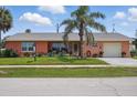 Attractive coral home with a well-kept lawn, mature palm trees, and inviting front yard at 100 Lynnhurst Dr, Ormond Beach, FL 32176