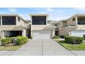 Rear view of townhome showcasing a two-car garage, screened patio, and well-maintained landscaping at 3411 Gallia St, New Smyrna Beach, FL 32168