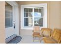 Inviting front porch area, features a cozy seating arrangement with two wooden chairs and a table near a window at 3257 Bailey Ann Dr, Ormond Beach, FL 32174