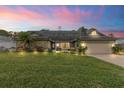 Charming single-story home at dusk featuring a stone accent wall, blue door and landscaped front yard at 13 Twin River Dr, Ormond Beach, FL 32174