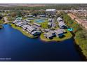 Aerial view of lakefront condos featuring tennis courts, mature landscaping, and community pool at 150 Limewood Pl # F, Ormond Beach, FL 32174