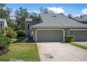 Charming exterior of a townhome featuring a well-maintained lawn, landscaping, and attached two-car garage at 25 Misners Trl, Ormond Beach, FL 32174