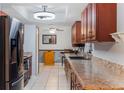 Galley kitchen featuring granite countertops, sleek black appliances, wood cabinets, and tile floors, perfect for cooking enthusiasts at 290 Birch Ave, Orange City, FL 32763