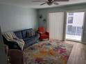 Cozy living room featuring a comfortable blue sofa, stylish rug, and natural light from sliding glass doors to a balcony at 3641 S Atlantic Ave # 212, Daytona Beach Shores, FL 32118