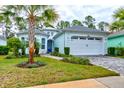 Charming one-story home featuring a two-car garage, a blue front door and landscaped front yard at 1068 Sea Shell Ct, Daytona Beach, FL 32124