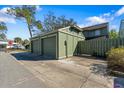 View of the detached single car garage and green wooden fence gate at the front of the townhome at 128 Pine Cone Trl, Ormond Beach, FL 32174