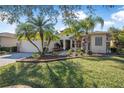 Beautiful single-story home with lush landscaping, mature palm trees, and a brick-paved driveway at 187 Indian Wells Ave, Kissimmee, FL 34759