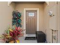 Charming front entrance with a neutral-colored door, potted plants, and a welcoming 'hello' doormat at 57 Bella Lago Cir, Port Orange, FL 32129