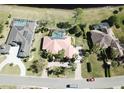 Birds-eye view of single-story home, featuring a terracotta roof, enclosed pool, manicured greenery, and serene neighborhood at 1317 Dovercourt Ln, Ormond Beach, FL 32174