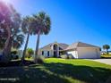 Inviting single-story home with a manicured lawn, palm trees, and attached two-car garage at 14 Sea Swallow Ter, Ormond Beach, FL 32176