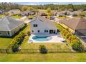 Aerial view of a backyard featuring a kidney-shaped pool, patio area, and manicured landscaping enclosed by a wrought iron fence at 225 Perfect Dr, Daytona Beach, FL 32124