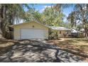 Charming single-story yellow home featuring a well-maintained lawn, mature trees, and an attached garage at 1432 Mollie Rd, Daytona Beach, FL 32114