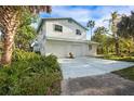 White two-story home featuring a two-car garage, tropical foliage, and a wide concrete driveway at 322 Garden St, Daytona Beach, FL 32114