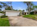 Single-story home boasts a two-car garage and mature landscaping, with a concrete driveway at 59 Amsden Rd, Ormond Beach, FL 32176