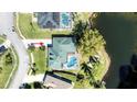 Aerial view of a well-maintained home featuring a private pool, lush greenery, and backing onto a serene pond at 6172 Knotty Pine Ct, Port Orange, FL 32127