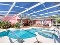 Inviting screened-in pool area with a jacuzzi, patio seating, and lush landscaping, perfect for outdoor relaxation at 6172 Knotty Pine Ct, Port Orange, FL 32127