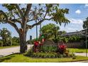 Community entrance sign featuring beautiful landscaping and mature trees at 1 Tomoka Oaks Blvd # 102, Ormond Beach, FL 32174
