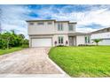 Two-story home shows neutral colors, a brick driveway, and green lawn at 32 Ocean Breeze Cir, Ormond Beach, FL 32176