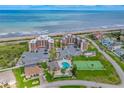 Aerial view showcases a beachfront condo with a community pool, tennis court, and oceanfront parking at 3370 Ocean Shore Blvd # 206B, Ormond Beach, FL 32176