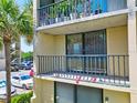 Exterior balcony area with railing, potted plants, and parking area in view at 1441 N Atlantic Ave # 211, Daytona Beach, FL 32118